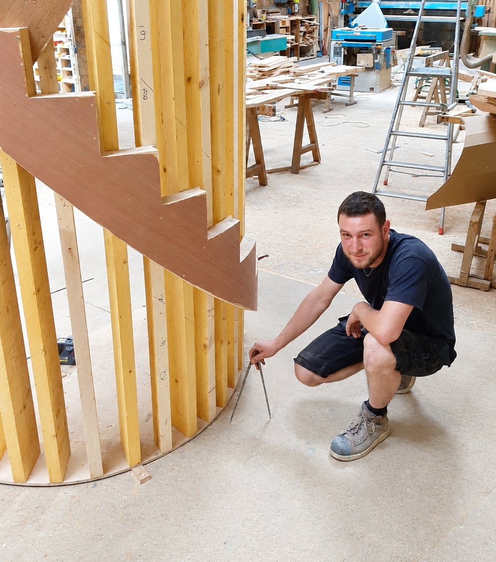 Martin Rocher, accroupi au pied d’un escalier hélicoïdal en cours de montage